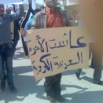 Syrian Kurds protest in Qamishli. The poster reads: "Long live Kurdish-Arabic brotherhood". Photo: Massoud Akko