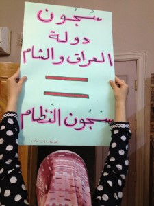 Suad holds up a placard that says "ISIS prisons= regime prisons." Photography by Zaina Erhaim.