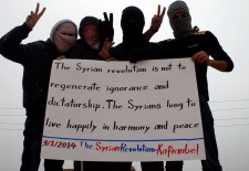 Activists in Kfar Nabel held this banner when ISIS still controlled the town. Photo credit: "Protest Banners of Occupied Kfar Nabel" page on Facebook.