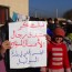 A member of al-Bouleil’s local council holds a sign expressing gratitude for donations from the Forum of Syrian Businessmen. Photo: Ahmad al-Bouleily