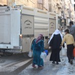 An elderly woman chases a fire engine to get water after the Amiriya neighbourhood of Aleppo is cut off.