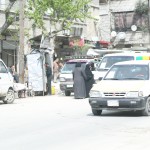 Two women in standing in front of a taxi in the Firdaws neighbourhood of Aleppo. Photographer: Hussam Kuwaifatiyah