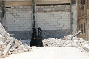 نساء يمشين في حي المعادي بين ركام القصف