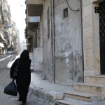 سيدة تحمل كيس وتسير في أحد الأحياء في حي الأنصاري في حلب. تصوير: حسام  كويفاتية