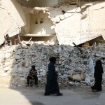 نساء يمشين بالقرب من بناء مهدم في بستان القصر في حلب. تصوير براء الحلبي