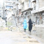 سيدة وأطفالها يقطعون الشارع أمام جسر الشعار المهدم في حلب. تصوير حسام كويفاتية