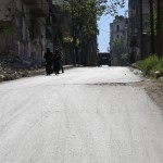 سيدتان تمشيان بالقرب من مدرسة مهدمة في حي الأنصاري. تصوير حسام كفويفاتية