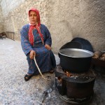 أمرأة نازحة من كوباني الى الشيخ مقصود تطبخ على الحطب. تصوير براء الحلبي
