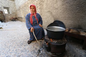 أمرأة نازحة من كوباني الى الشيخ مقصود تطبخ على الحطب. تصوير براء الحلبي