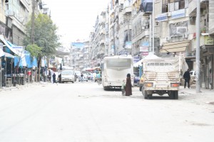 A woman and her child walk through a market in Aleppo’s Al-Shaar neighbourhood. Photo: Hussam Kuwaifatiyeh